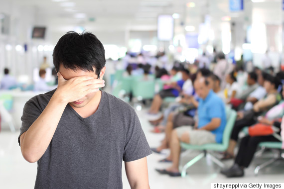 serious man holding his head, headache with blur hospital background